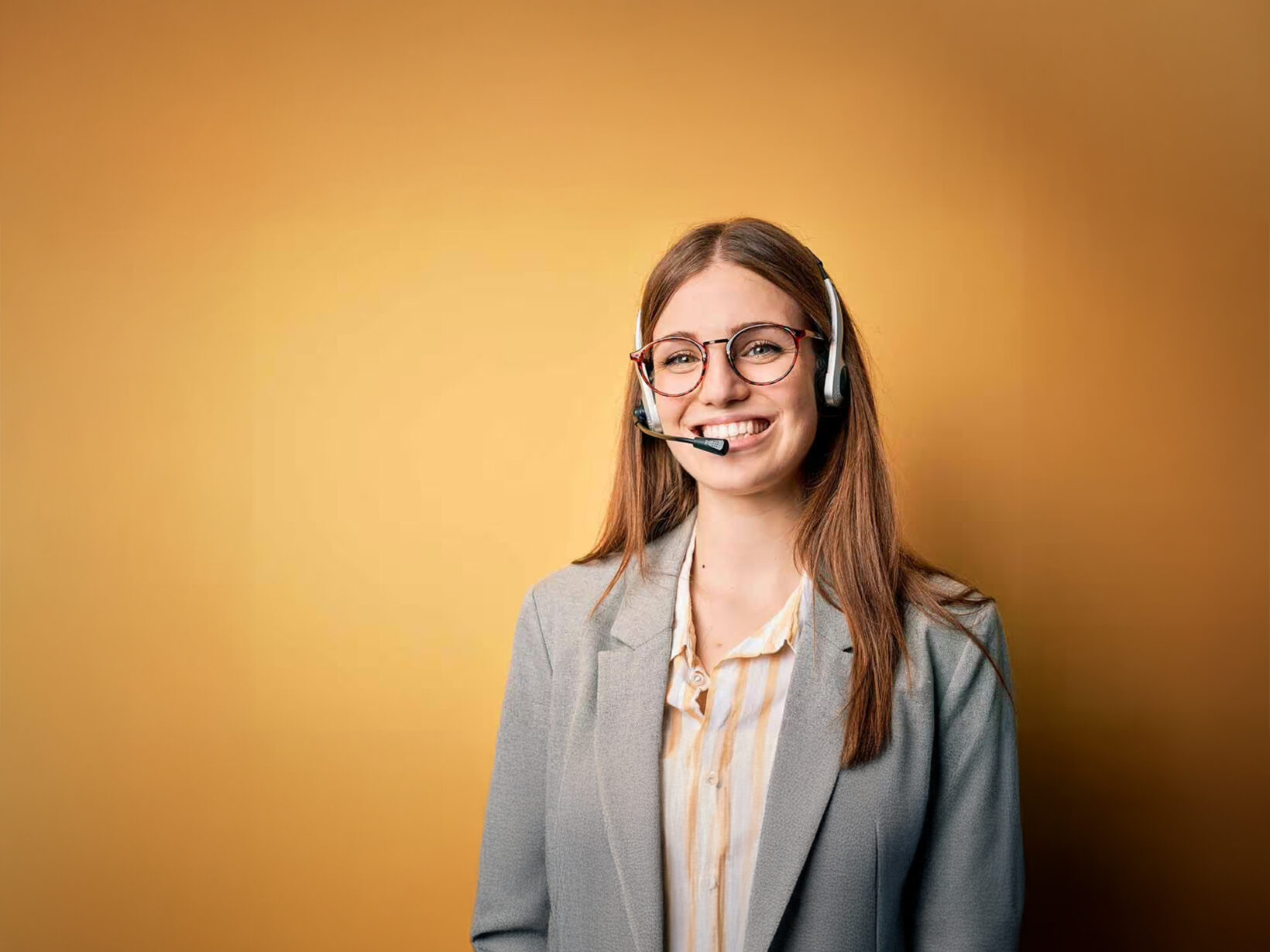 Freundliche Kundenberaterin mit Headset und Brille vor gelbem Hintergrund, bereit, Unterstützung zu bieten.